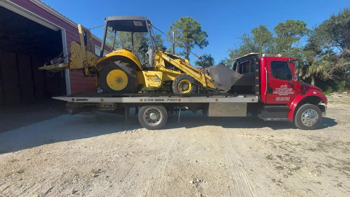Yellow backhoe loader on the red flatbed