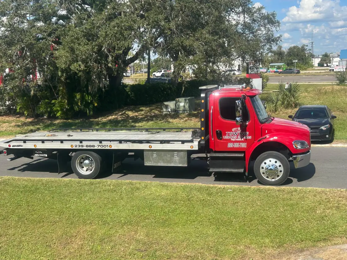 Red flatbed tow truck with an empty bed, ready for the next job