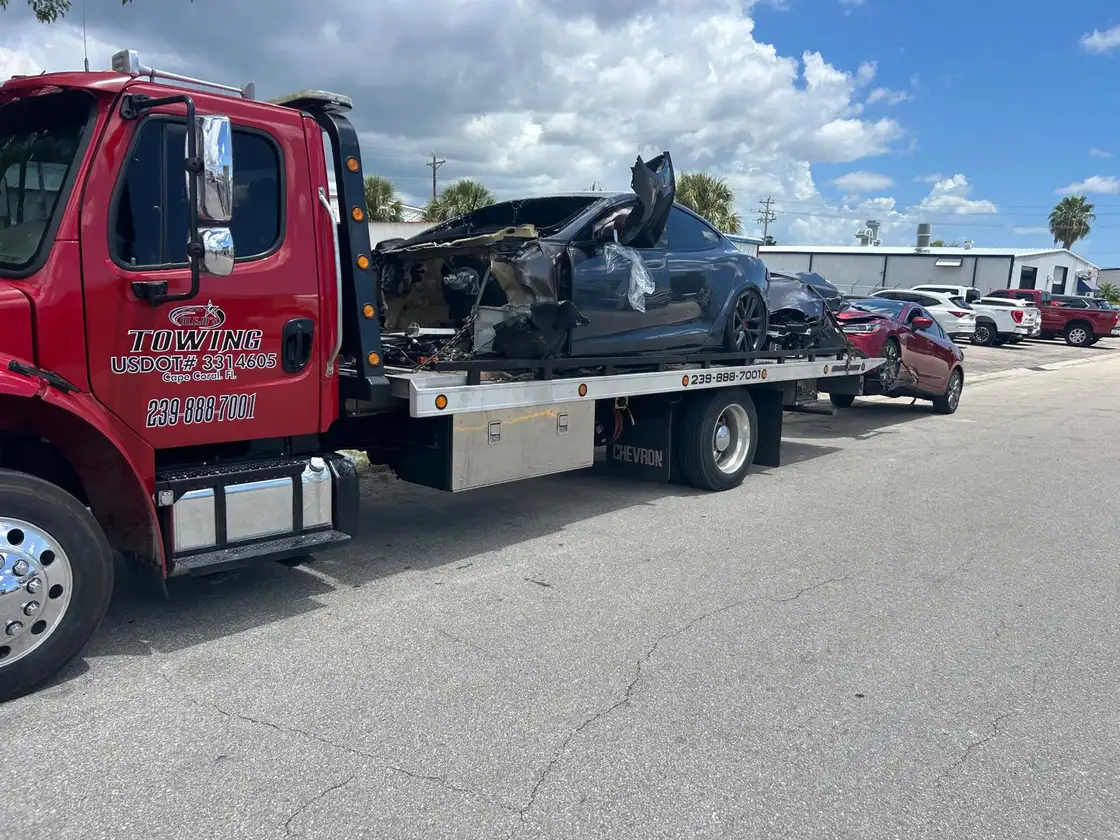 Badly damaged car loaded on the red flatbed after a crash